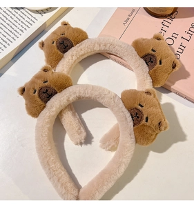 Detail of plush beige headbands featuring cute brown stuffed capybara ornaments