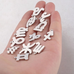 Detailed macro view of twelve silver stainless steel zodiac charms held in a palm