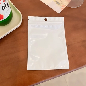 Detailed view of a white opaque resealable bag with hanging hole on a wooden background