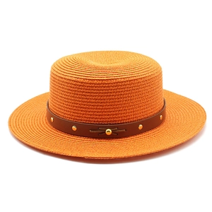 Détail d'un chapeau de paille orange avec bande en cuir marron et rivets dorés