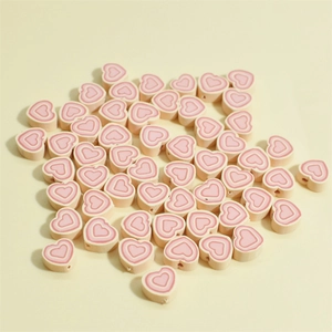 Vue détaillée de perles de coeur de 10mm en pâte polymère rose avec motifs concentriques