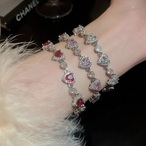 Close-up of three luxury heart-shaped zircon bracelets in pink, red, and white gems