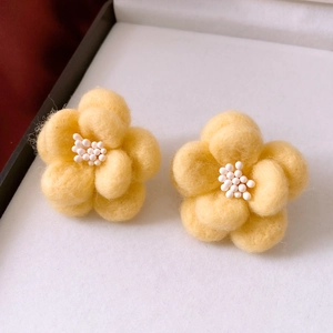 Detail of yellow wool felt flower earrings with delicate white pearl bead center