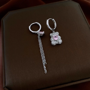 Detail of asymmetrical silver earrings with crystal teddy bear and pink heart gemstones
