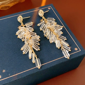 Detail of gold tassel earrings with crystal rectangular beads and star studs on a gift box