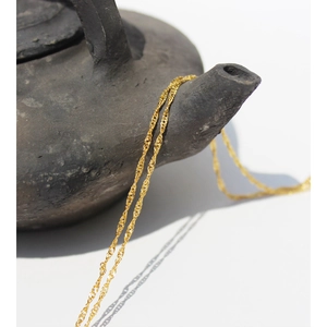 Retro double-sided relief pendant necklace in gold finish on a creative dark teapot background