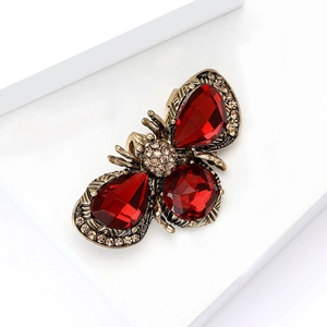 Detailed close-up of a vintage bee brooch with red gems and champagne crystals