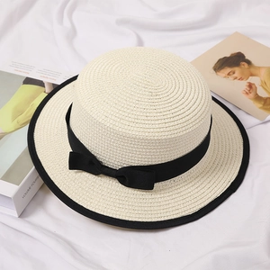 Detail of white boater hat with black ribbon bow and fine straw weave texture