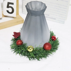 Close-up of a grey frosted glass vase with a Christmas wreath and plaid bow ornament