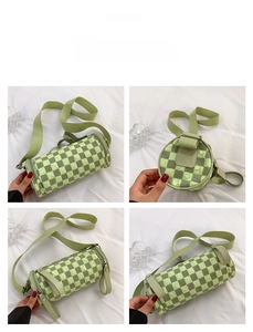 Detail view of a green checkerboard cylinder crossbody bag with wide shoulder strap