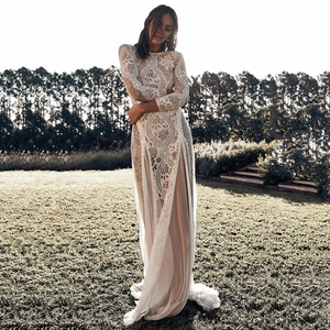 Elegant white lace long sleeve wedding dress with backless detail and floor-length skirt