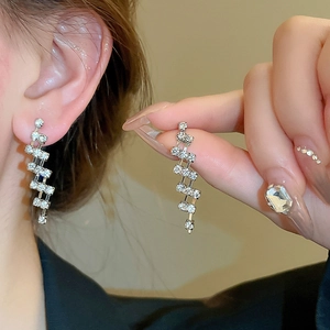 Macro view of silver geometric tassel earrings with white zircon layered drop design