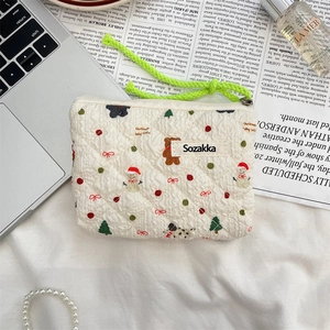 Detailed close-up of a floral quilted cotton makeup bag with Christmas patterns and green cord