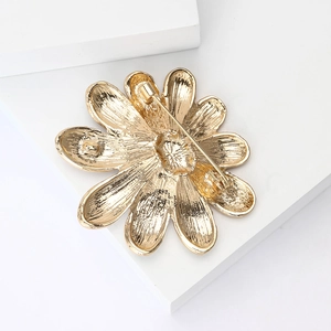 Detailed back view of a golden flower brooch showing the secure metal pin fastening mechanism