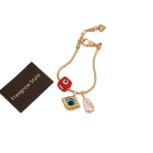 18K gold plated charm bracelet featuring evil eye pendants and baroque pearl detail