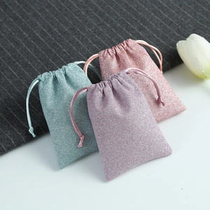 Glitter drawstring jewelry pouches in cyan, pink, and purple with elegant white tulip decoration