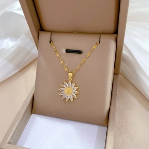Close-up of golden sunflower pendant with white zircon stones on a silk jewelry display