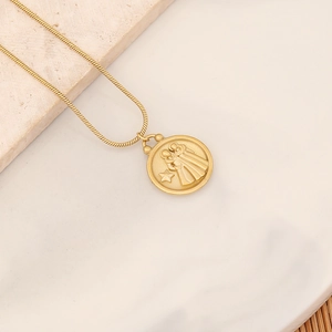 Goldene Schlangenkette mit Sternzeichen-Reliefanhänger auf Marmor- und Holzuntergrund