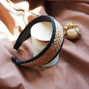 Detail of woven raffia headband in brown and black stitching on a neutral background