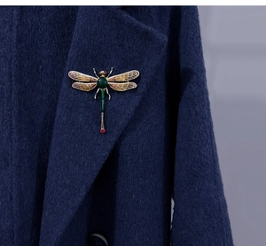Detailed close-up of a large dragonfly brooch with green enamel on a blue wool coat