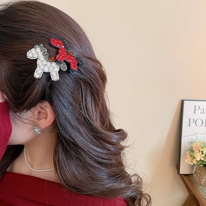 Detail shot of a sparkling rhinestone horse hair clip and red butterfly pin on hair