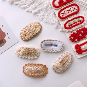 Detailed close-up of handmade knitted flower hair clips with silver metal duckbill base