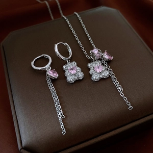 Detailed macro view of silver bear jewelry set with pink gemstones on brown box