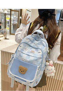Close-up of light blue aesthetic backpack with plush bear embroidery and rabbit pendant