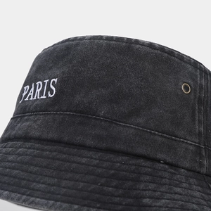 Macro shot of washed black bucket hat with PARIS embroidery and copper eyelet detail