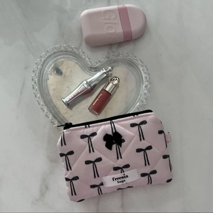 Detailed close-up of a pink quilted makeup bag with a black bow and heart accessories