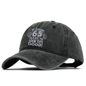Detail of 65 years birthday embroidery on a washed dark gray cotton baseball cap