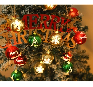 Macro view of Christmas LED ball lights with festive prints on a snowy tree