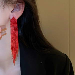 Close-up of red rhinestone tassel drop earrings worn by a model in a black suit