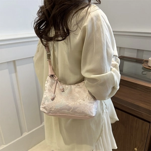 Pink brocade New Chinese style handbag with pearl charm shown on model's shoulder