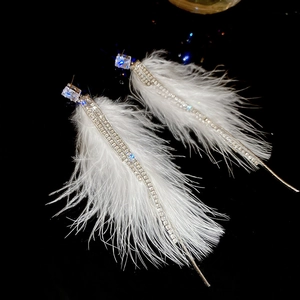 Detailed view of white feather tassel earrings with sparkling rhinestone fringe details