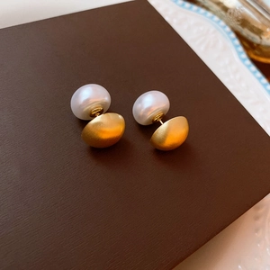 Detailed macro shot of elegant pearl stud earrings with matte gold finish on textured base