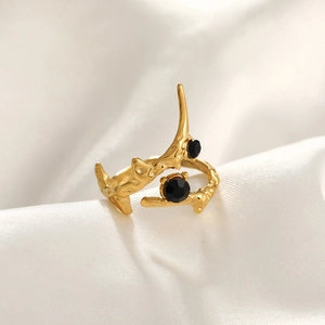 Detail of gold hammer-textured ring with two black stones on white silk fabric
