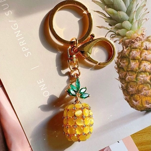 Macro detail of pineapple keychain with yellow opal and green crystals on gold metal