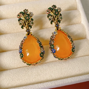Macro detail of vintage floral drop earrings with large orange pear-shaped resin stones
