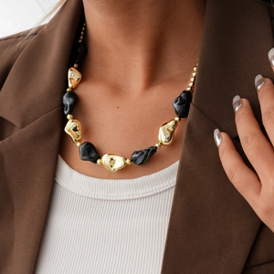 Detail of acrylic bead necklace with gold metallic and marble textures on a model