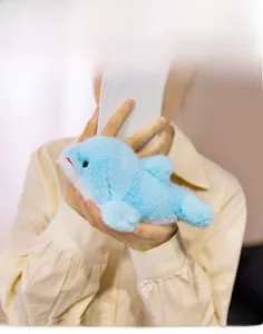 Détail d'un dauphin en peluche bleu doux avec une fourrure longue tenu en mains