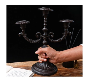 Close-up of vintage 3-arm iron candelabra with classic scrollwork and rustic texture