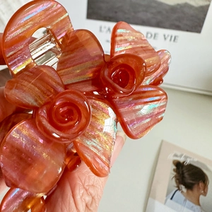 Elegant orange floral claw clip with golden glitter details for women hair styling