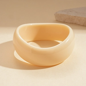 Detail of minimalist wide-band acrylic bangle with beige marble texture and smooth finish
