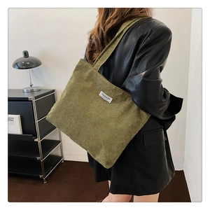 Detailed texture of olive green corduroy tote bag with fashion label and shoulder strap