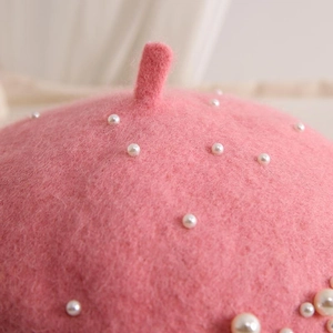 Close-up of pink wool beret featuring delicate white pearls and soft textured finish