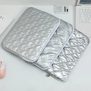 Quilted silver laptop sleeve with heart and bow patterns in a modern workspace setting