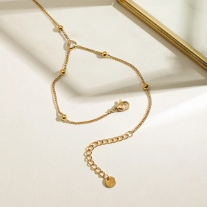 Detail of gold heart-shaped zircon bracelet with metal beads and lobster clasp closure