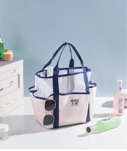 Detailed view of white mesh beach bag featuring blue straps and multiple side pockets