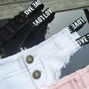 Dettaglio di pantaloncini di jeans neri, bianchi e rosa con bordi sfrangiati e scritte stampate